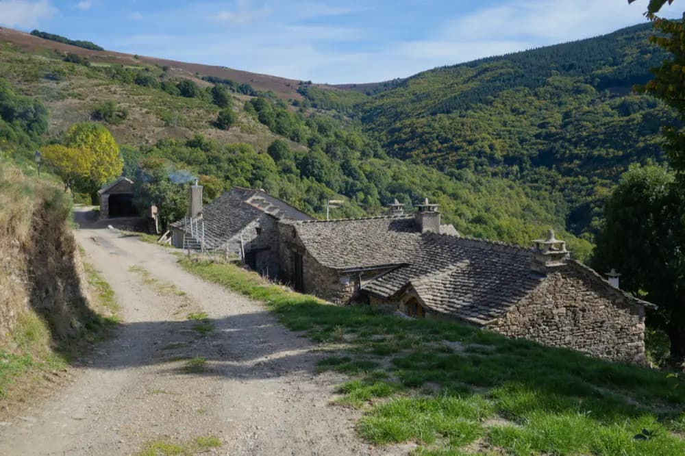 Maisons de pierre alignées le long d'un chemin, sur une pente rurale