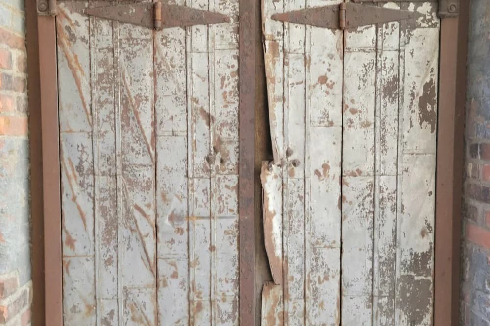 Double porte ancienne aux gonds rouillés et à la peinture usée