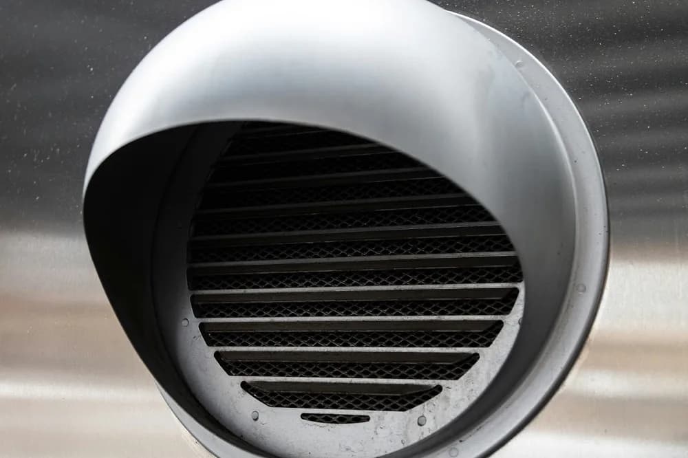 Grille ronde d'extraction d'air encastrée dans une paroi métallique