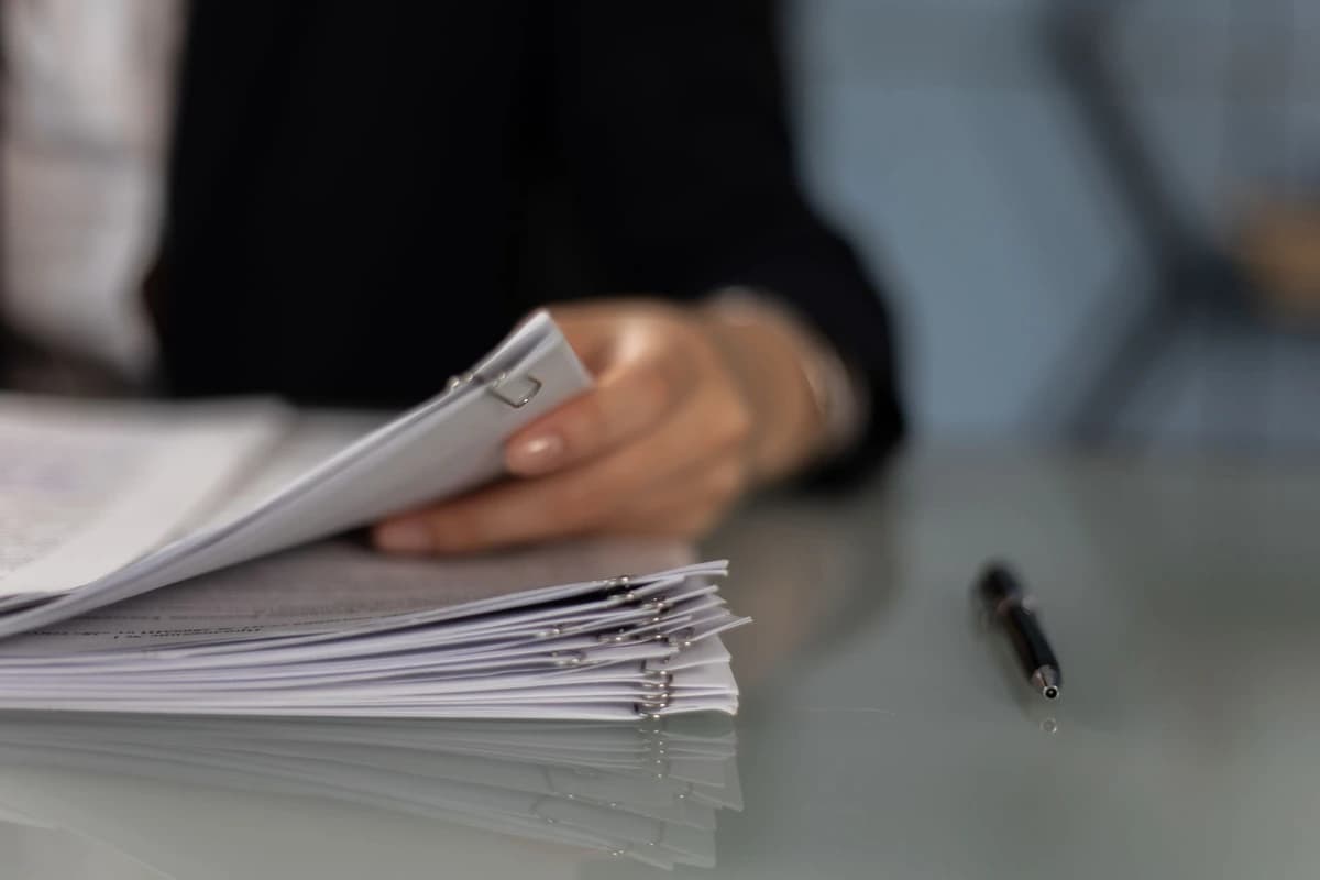 Une main tient un rapport imprimé, le document au premier plan