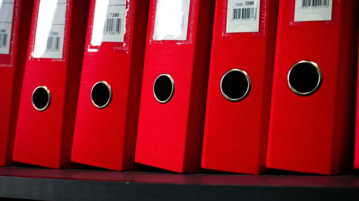 Classeurs à levier rouges alignés sur une étagère d'archives